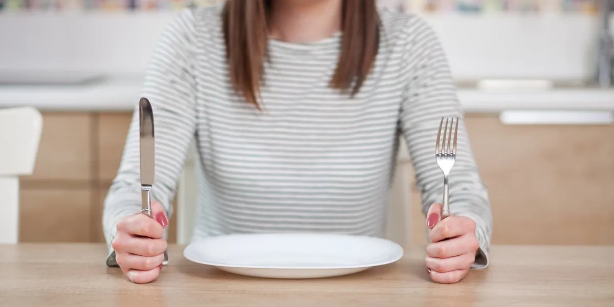 displeased young woman sitting at the empty plate shallow depth of field, focus on foreground