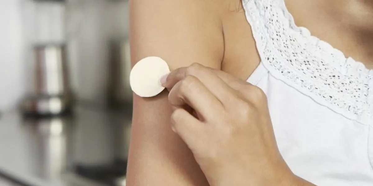 woman applying patch to arm, indoors, close-up