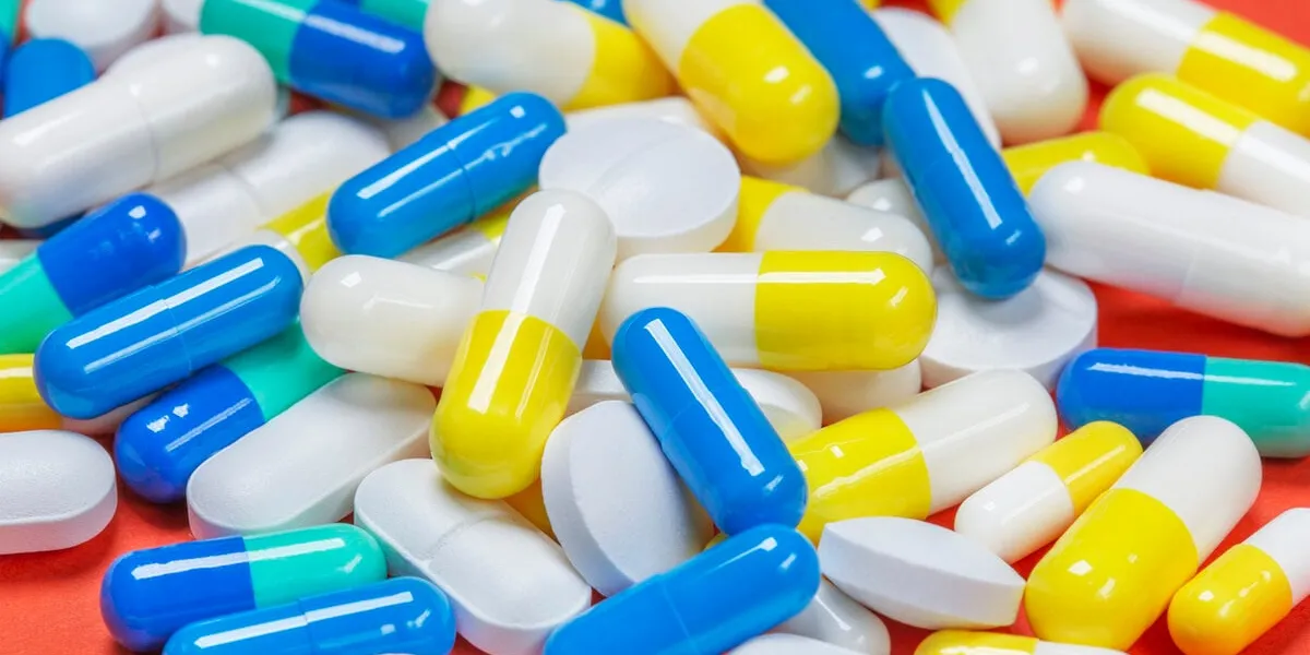 colored pills, pills and capsules on a red background