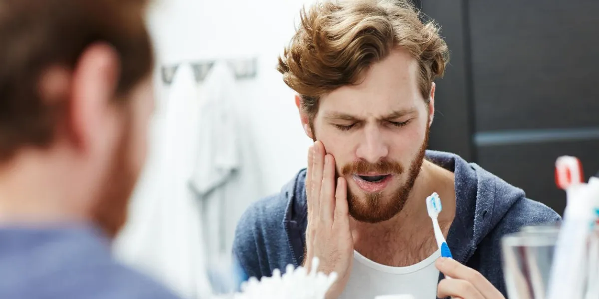 man with sensitive teeth touching his cheek