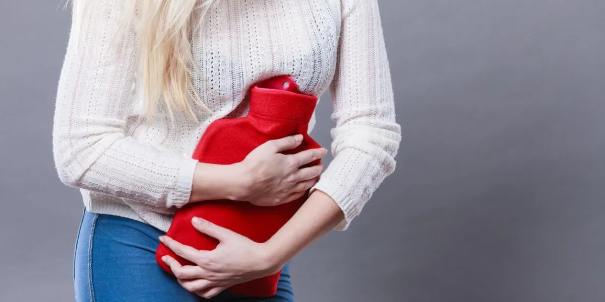 périodes douloureuses et les problèmes de crampes menstruelles concept de femme à avoir des crampes d'estomac sentiment très malade tenant une bouteille d'eau chaude