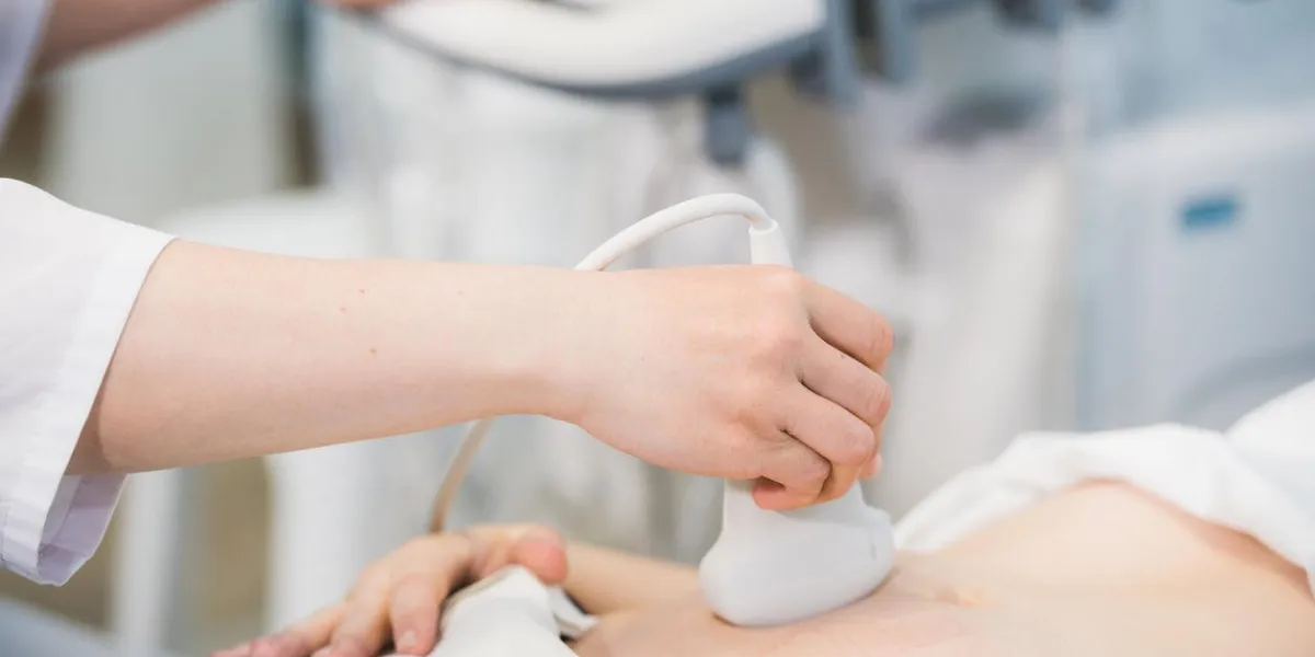 close-up of doctor moving ultrasound probe on pregnant woman's stomach in hospital