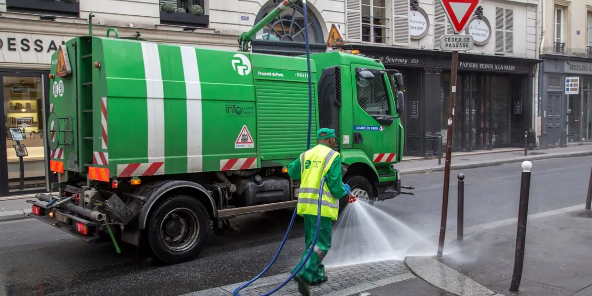 paris, france - july 24, 2017  a sweeper car and a worker cleaning the streets