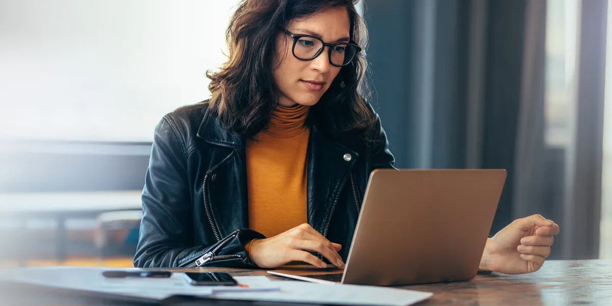 asian business woman sitting at a table in an office, typing on her laptop with focus young female professional showing a dedication and commitment to her project at work