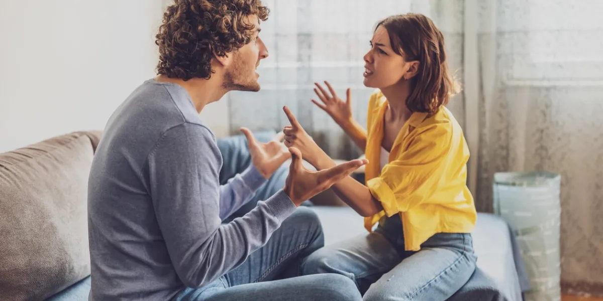 man and woman are sitting at sofa and arguing relationship problems