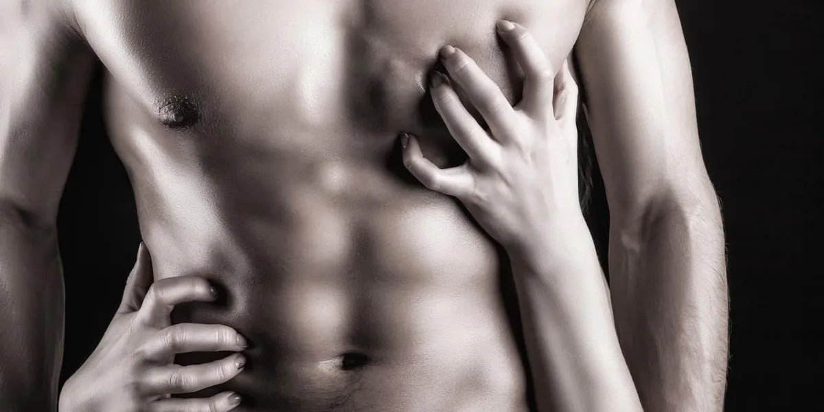 sexy muscular naked man and female hands on a dark background