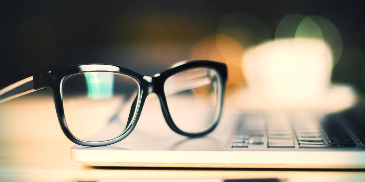 lunettes sur ordinateur portable avec un stylo sur la table en bois, gros plan