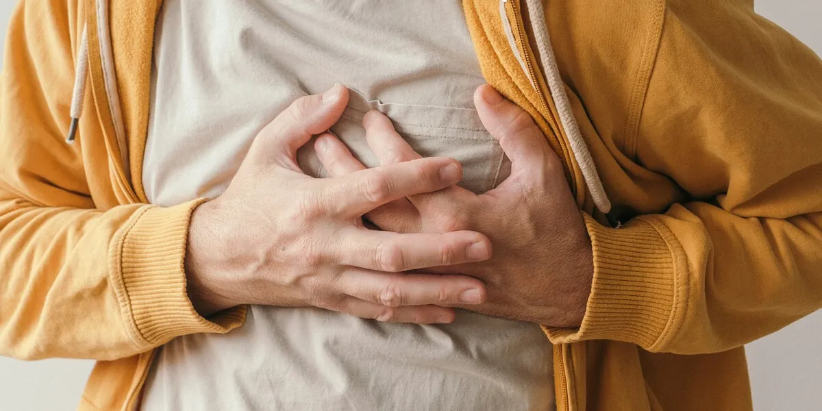 aching heart and heart attack, adult male with painful grimace pressing the upper abdomen with his hands to ease pain