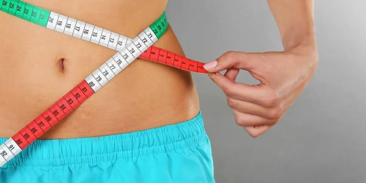 femme mesurant sa taille sur fond de couleur