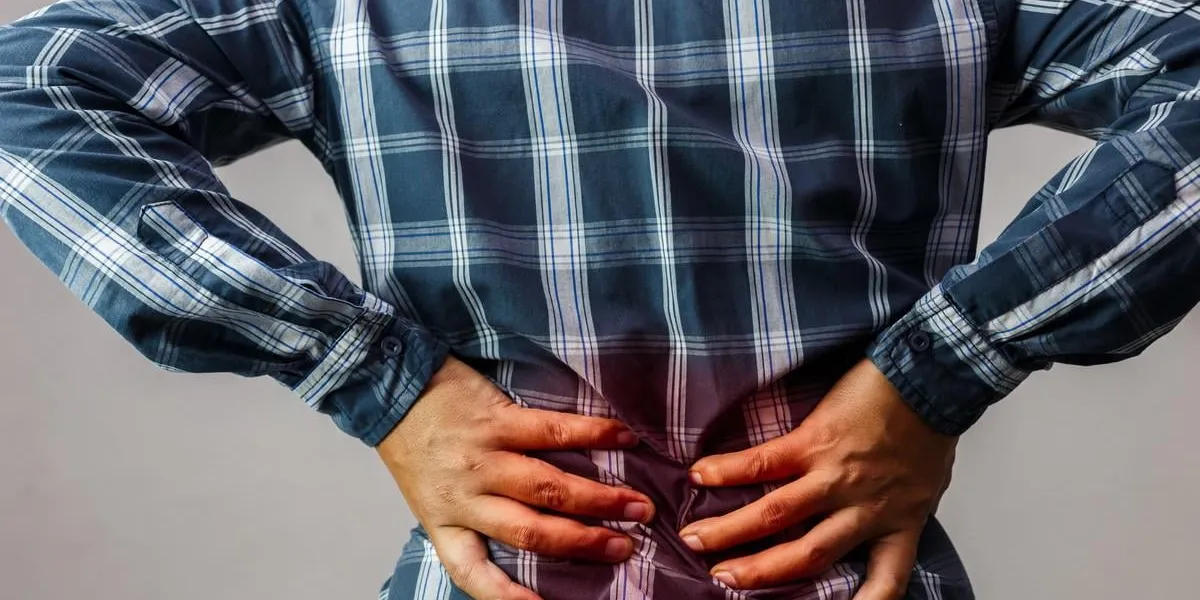 men with low back pain on a gray background   medical and health concepts