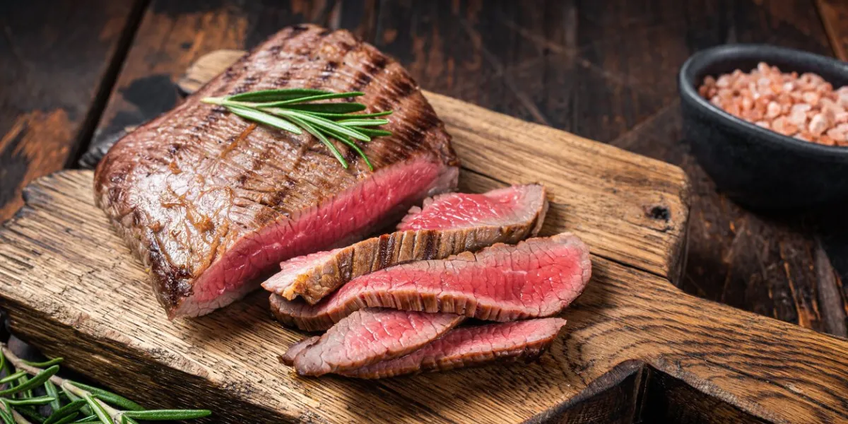 barbecue dry aged wagyu flank steak on a cutting board wooden background top view