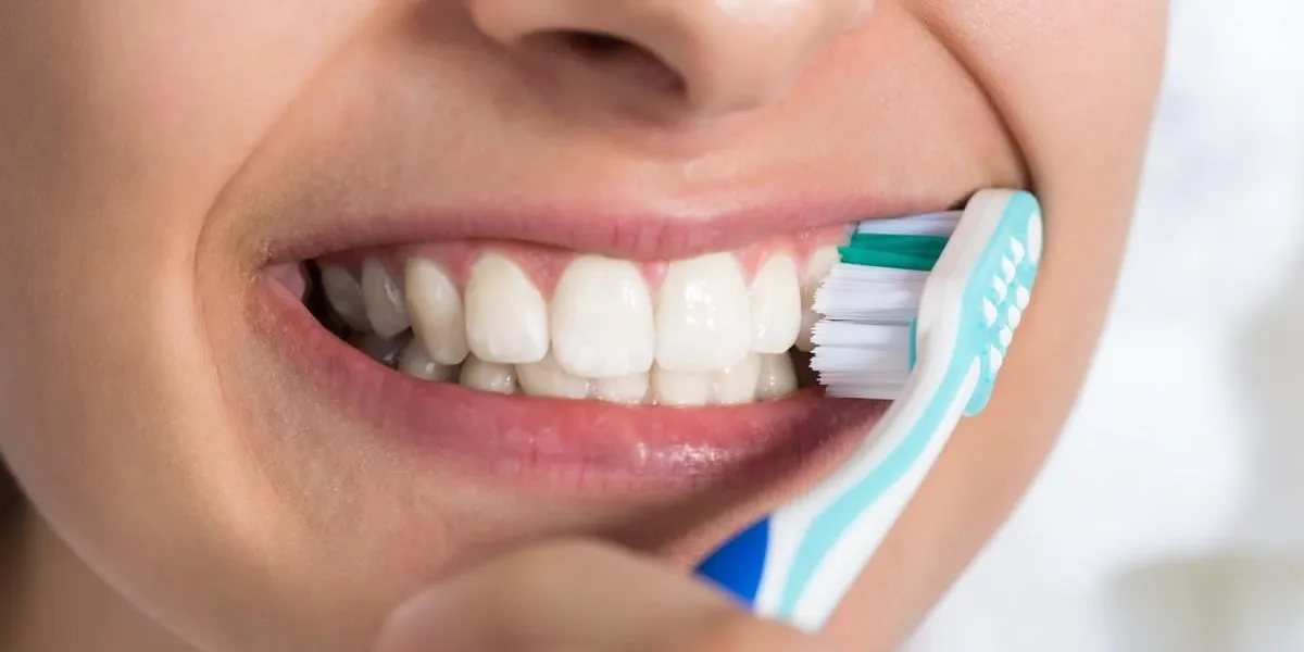 closeup of young woman brushing teeth at home