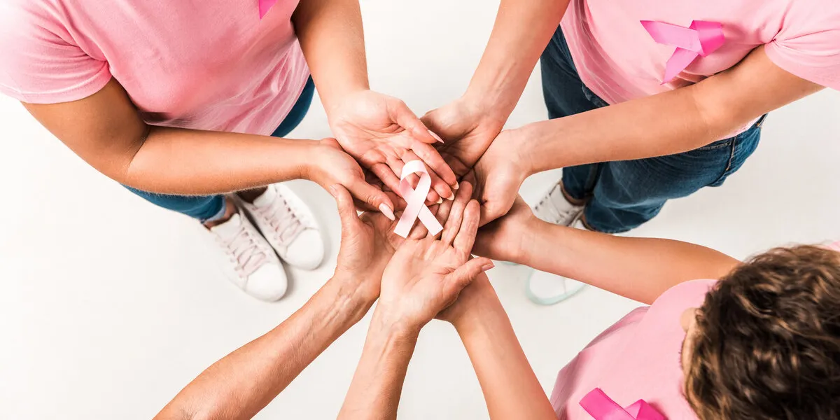 cropped shot of women in pink t-shirts holding breast cancer awareness ribbon isolated on white