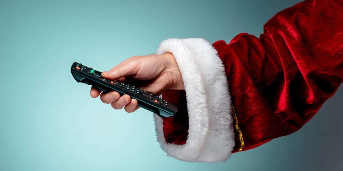 santa claus holding tv remote control on blue background
