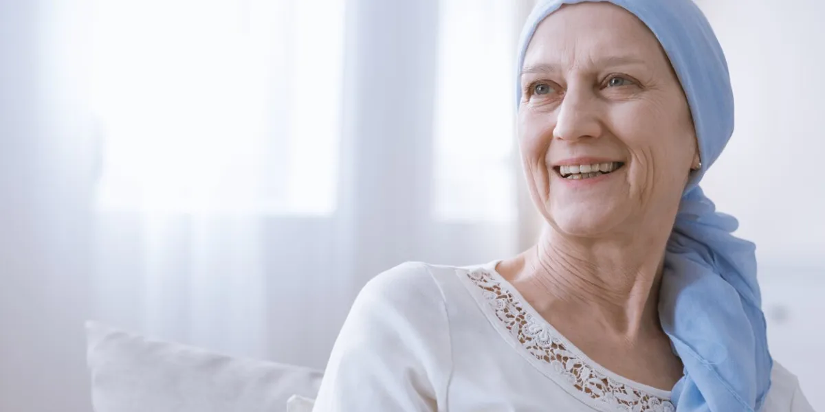 happy woman with cancer in blue headscarf smiling with hope