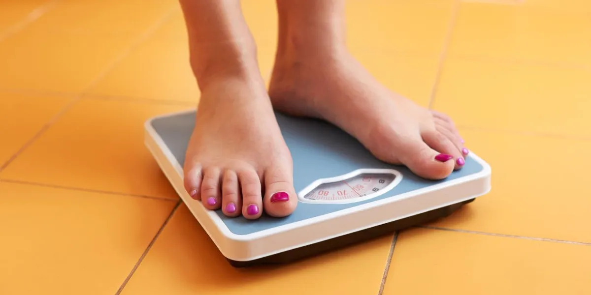 une paire de pieds féminins debout sur une balance de salle de bain