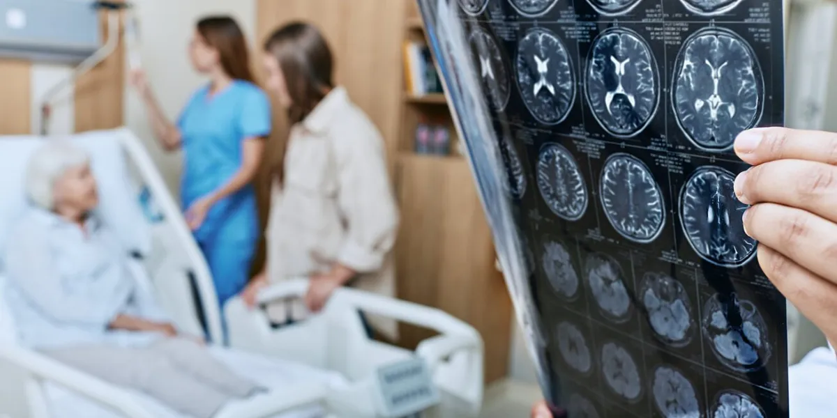 mri of head of elderly woman in hands of doctor standing in medical ward near senior patient with relative and nurse recovery after a stroke