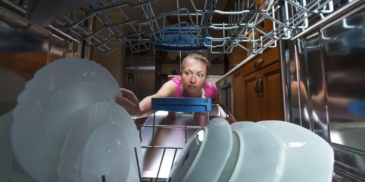 girl in the kitchen gets a plate from the dishwasher