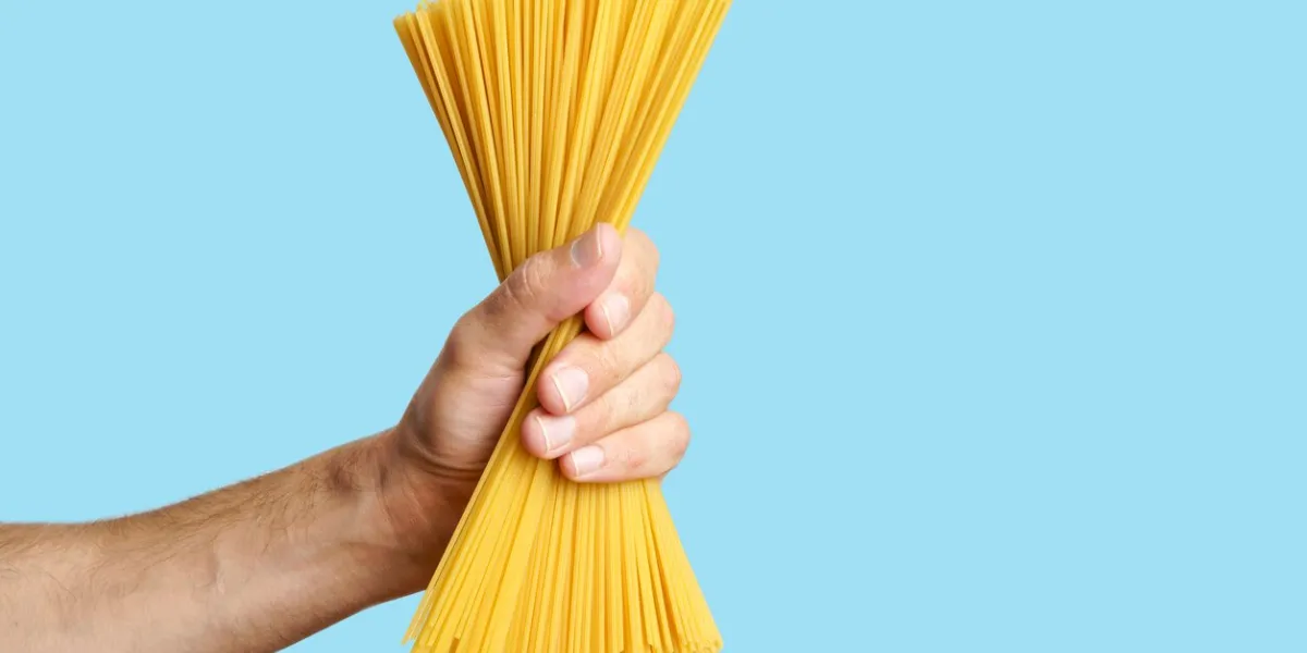 spaghetti pasta in hand on a blank background raw italian spaghetti before cooking and eating italian food high quality photo