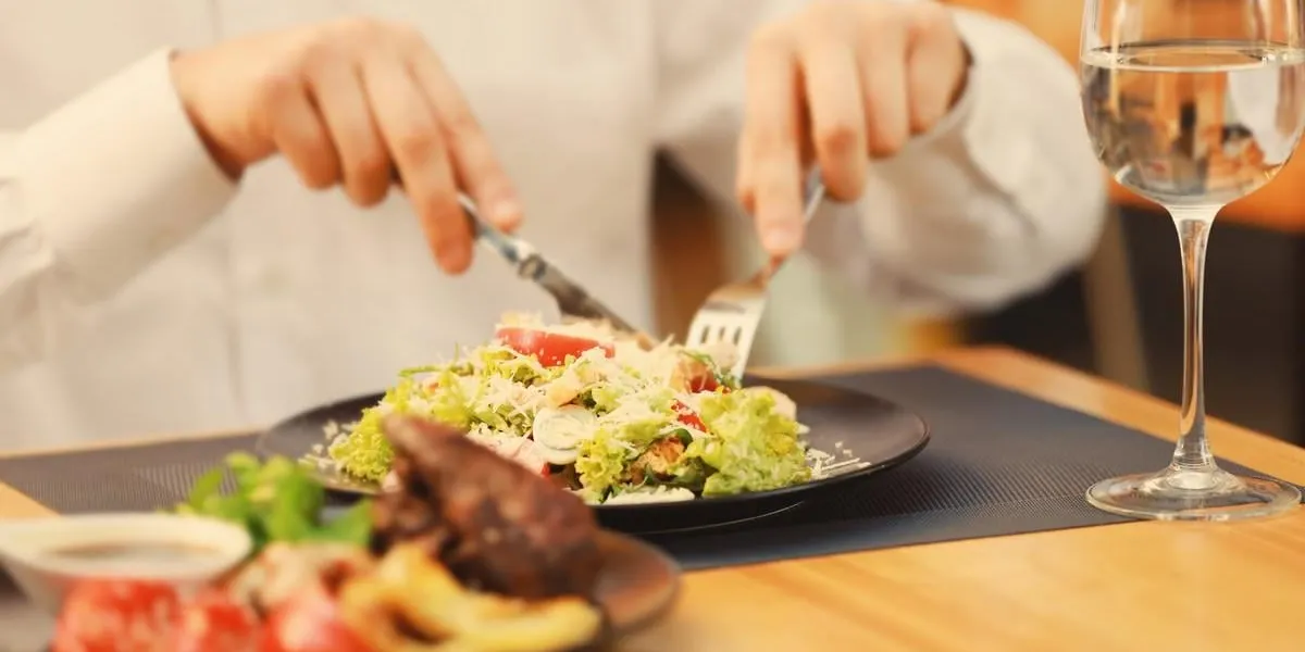 client eating tasty caesar salad in restaurant, close up