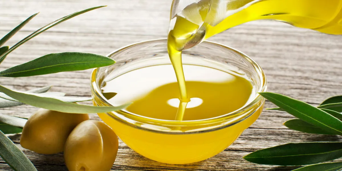 bottle pouring virgin olive oil in a bowl close up