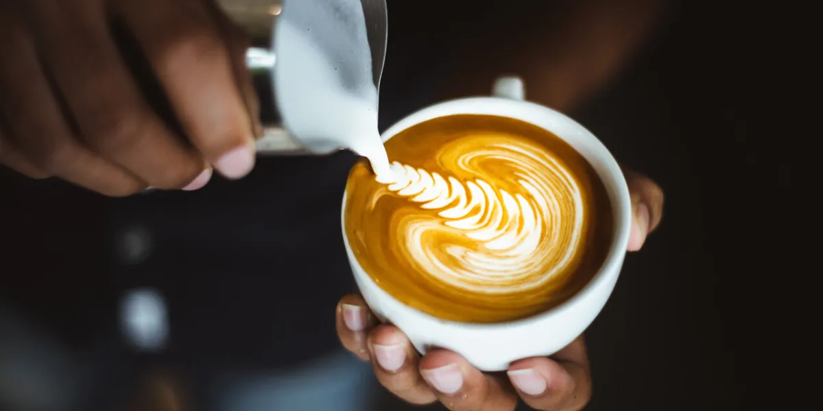 barista making a cup of coffee latte art in coffee shop