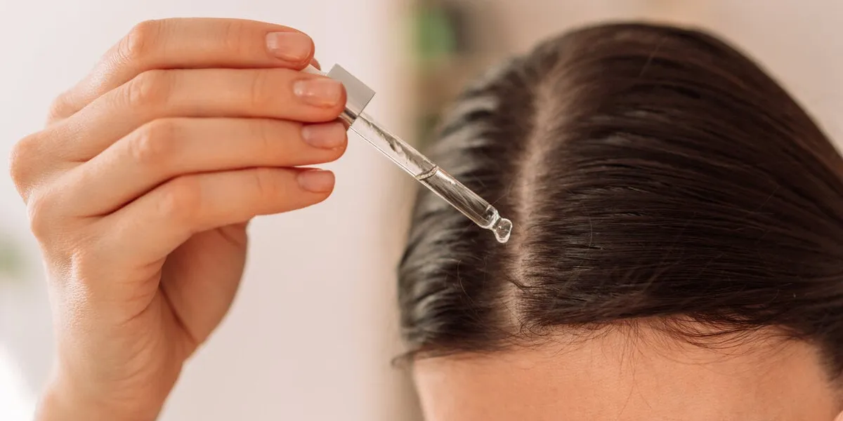 lady dripping hair oil with pipette on her hair