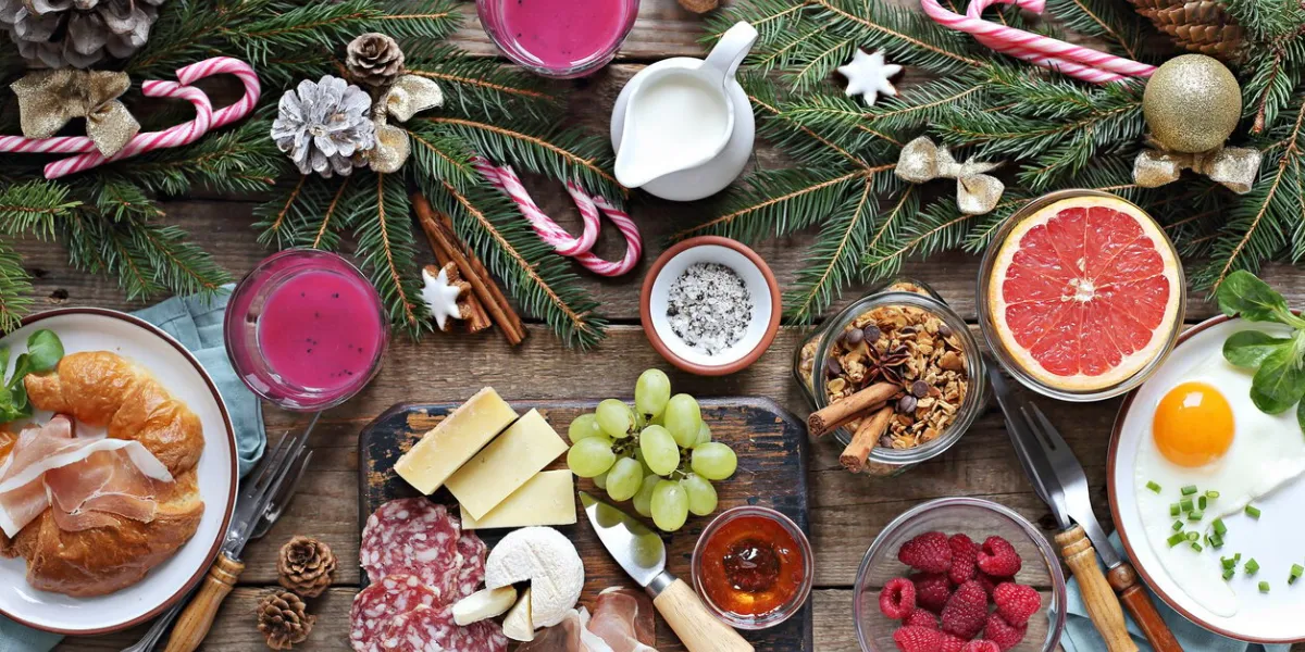 christmas brunch or breakfast table festive brunch set, meal variety with fried egg, appetizers platter, croissant, granola, smoothy and traditional sweets overhead view