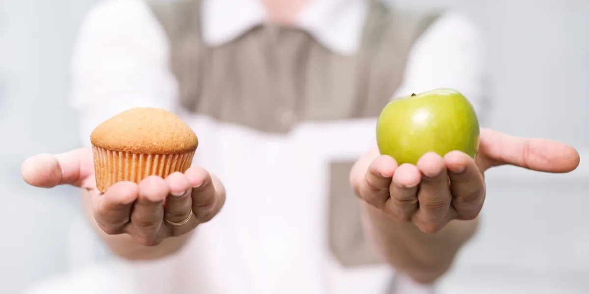 médecin un dentiste un homme tient une pomme verte et un cupcake sucré et montre sur les échelles un choix d'utile contre nocive