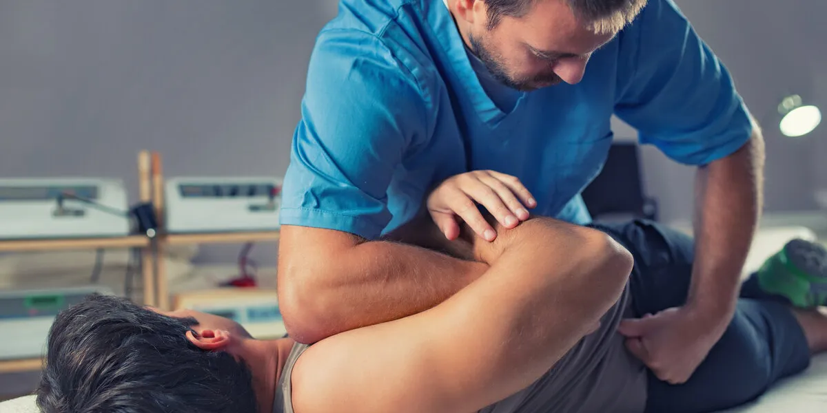 physiotherapist doing healing treatment on man's back therapist wearing blue uniform osteopathy chiropractic adjustment, patient lying on massage table