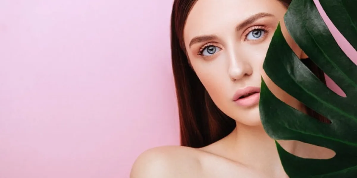 beauty woman with natural green palm leaf portrait, model girl with perfect makeup, natural eyeshadows brunette beautiful fashion model girl face skin care perfect skin on pink background