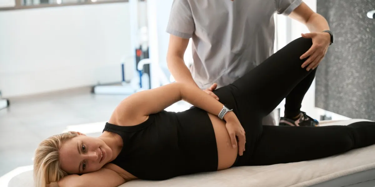 male chiropractor working with his back expectant mother, woman lies on massage table