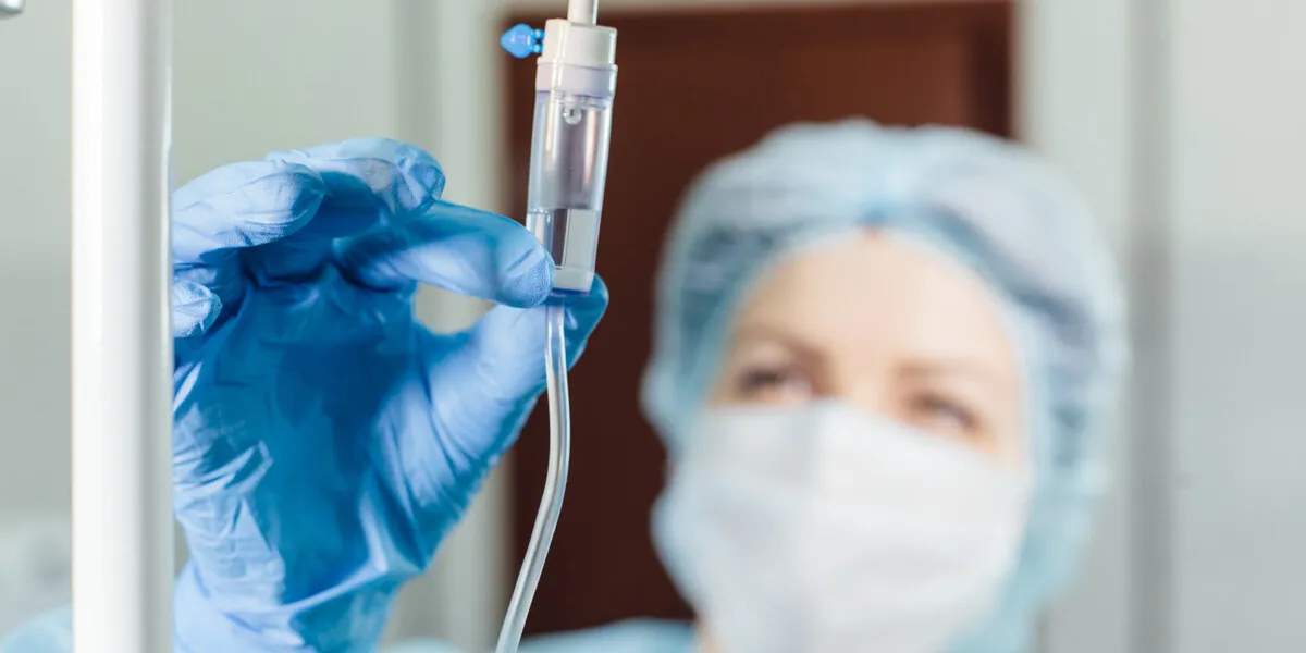 nurse connecting an intravenous drip in hospital room