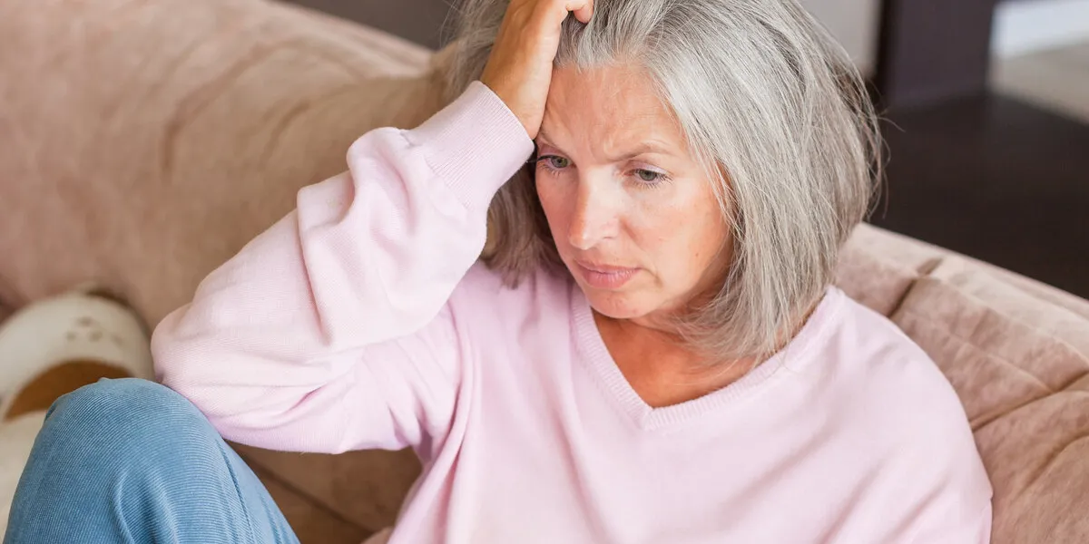 depressed mature woman sitting on sofa at home unhappy alon gray haired female in living room