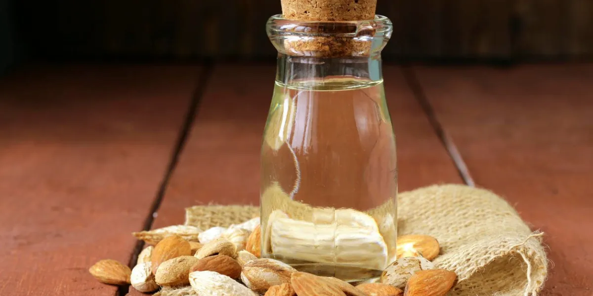 huile d'amande dans une bouteille en verre avec des noix entières