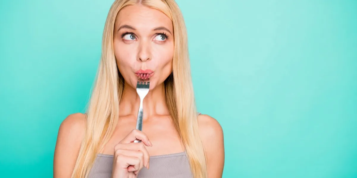 close-up portrait of her she nice attractive lovely sweet feminine girlish, straight-haired girl holding in hand kitchen ware licking fork isolated on bright vivid shine green blue turquoise background