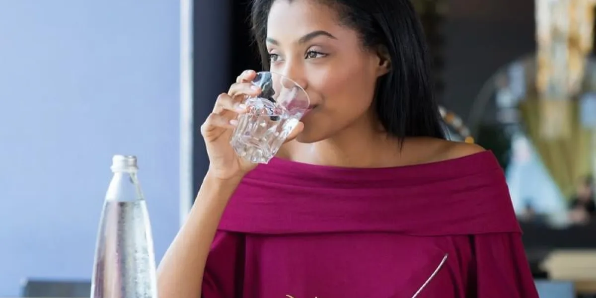 gros coup de jeune femme buvant un verre d'eau fille africaine boire de l'eau pendant sa pause déjeuner au restaurant une belle fille assoiffé boire un verre d'eau et regarder loin