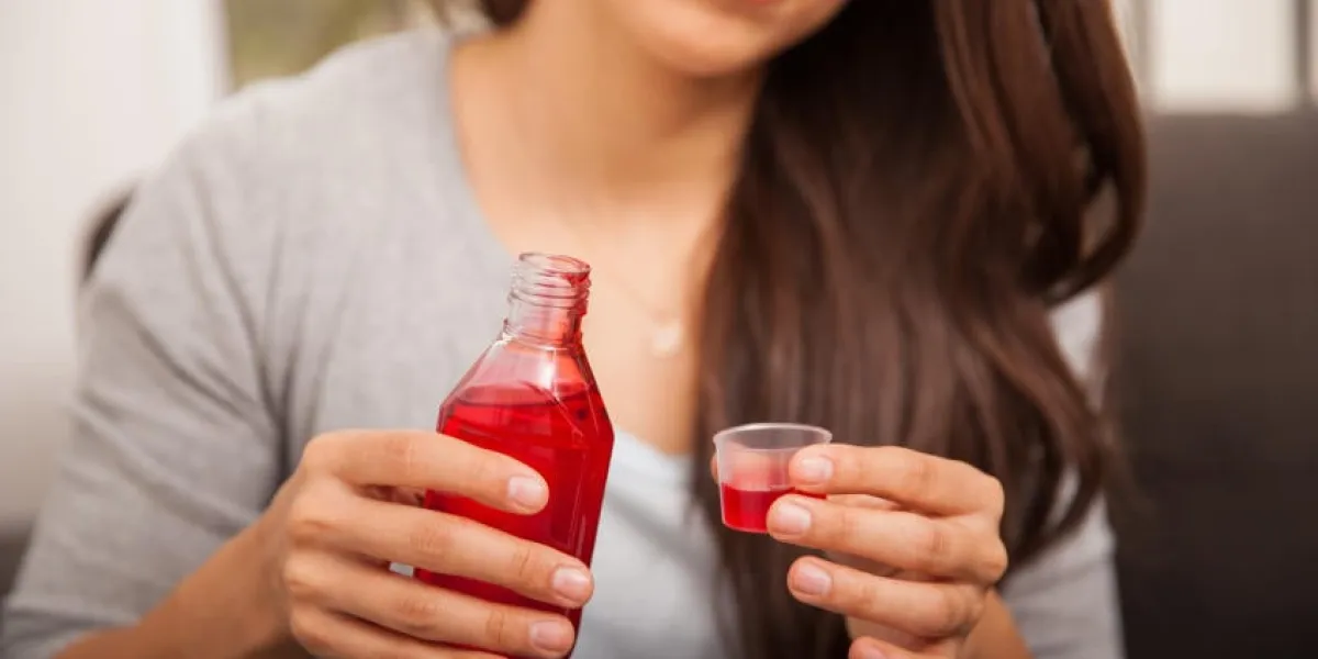 gros plan d'une jeune femme malade sur le point de boire du sirop contre la toux à la maison