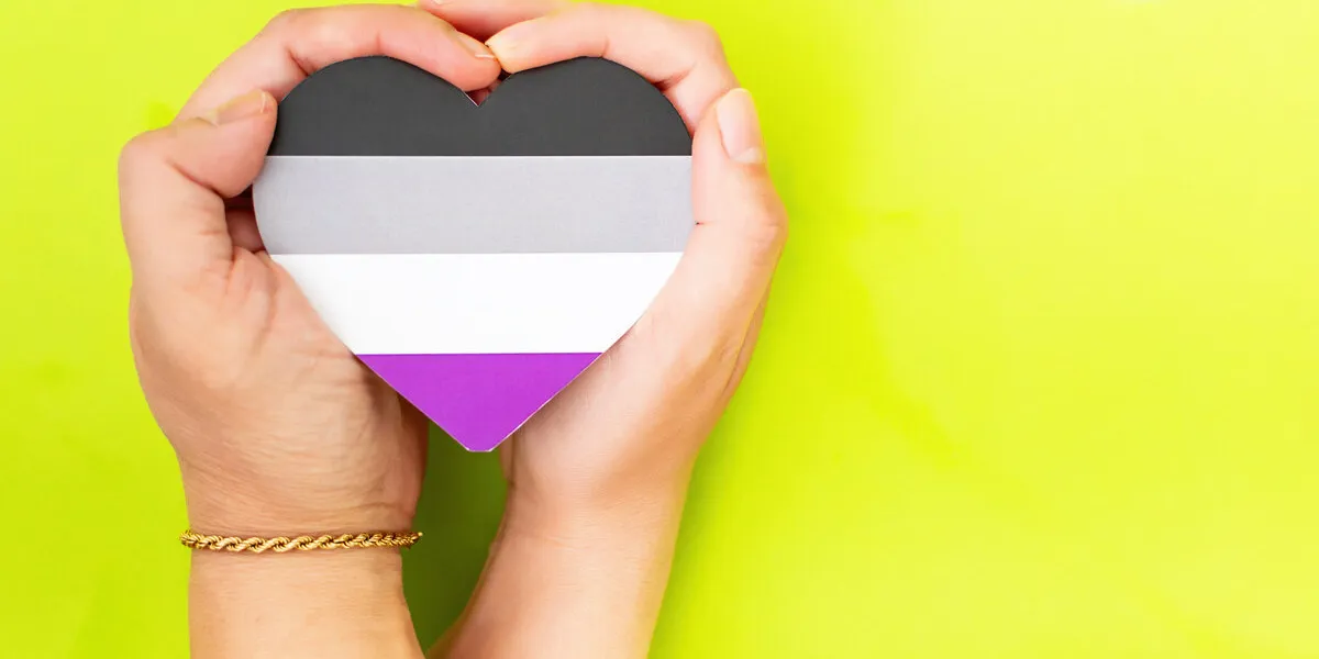 woman hands hold heart in the colors of asexual flag on green background lgbt concept, pride month top view, copy space