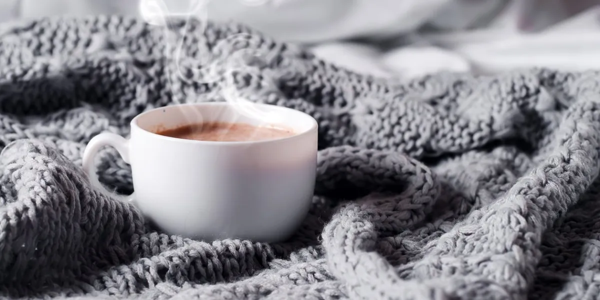 having a cup of coffee on gray blanket in bed