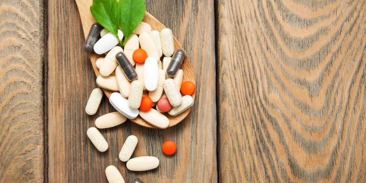 pilules sur la cuillère avec des feuilles sur un fond en bois