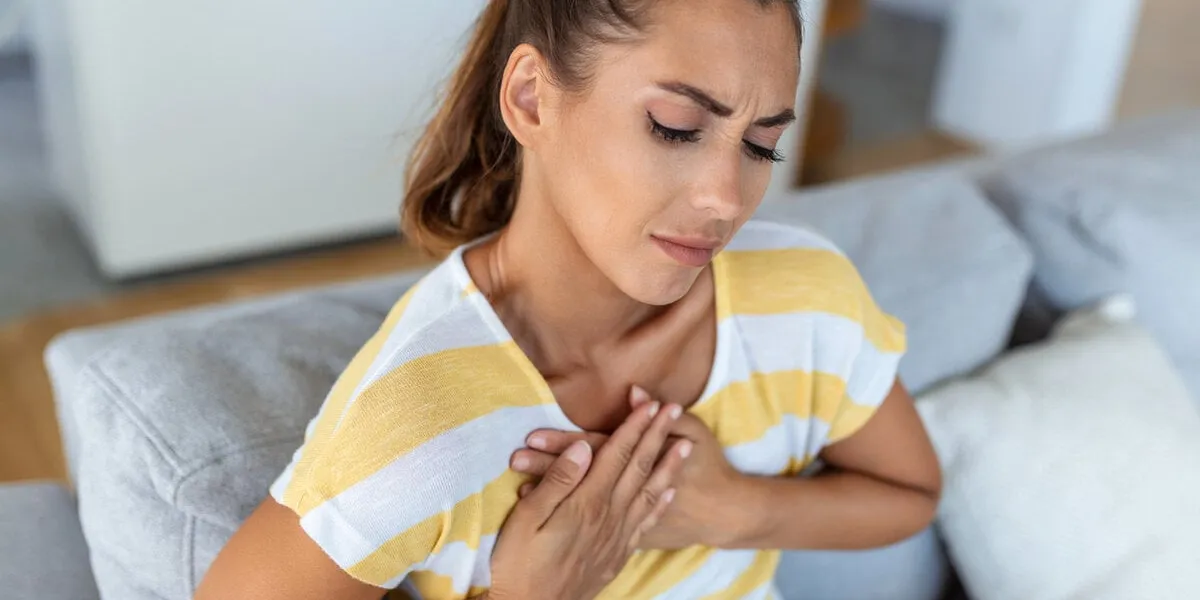 stressed young woman feeling pain and touching chest suffer from heartache disease at home while having heart attack, infarction