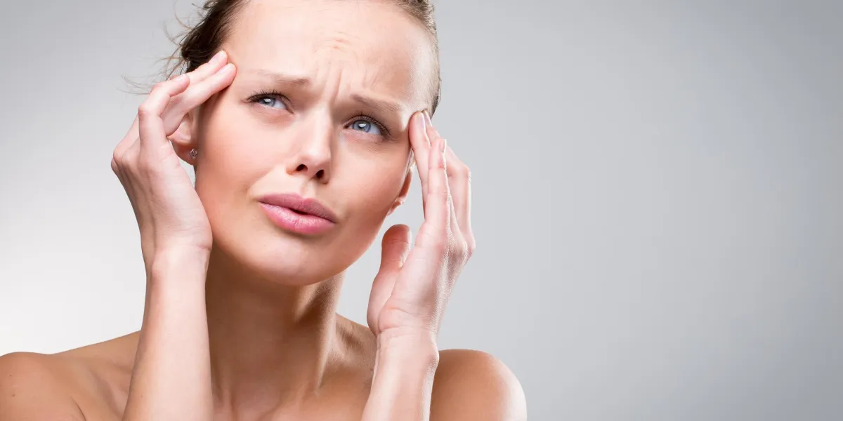 belle femme souffrant de maux de tête aiguë sur fond propre gris