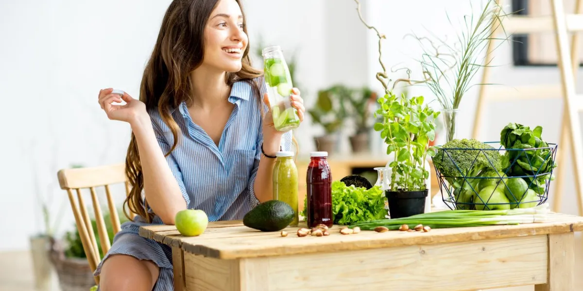beautiful woman sitting with healthy green food and drinks at home vegan meal and detox concept