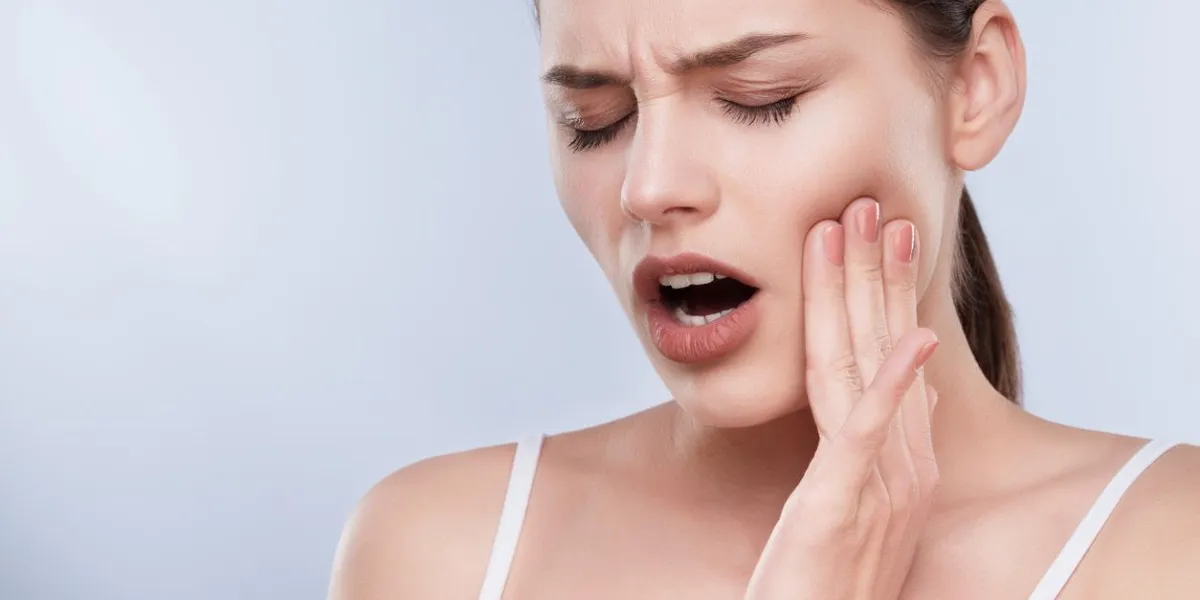 toothache, white teeth head and shoulders of young woman suffering from toothache, teethcare painful expression on face of woman, hands near face, closed eyes