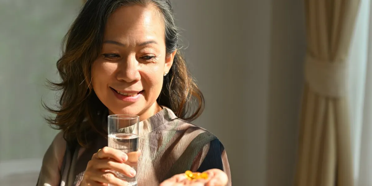 happy mature sixty year old female holding omega 3 supplement capsule, time to take medications