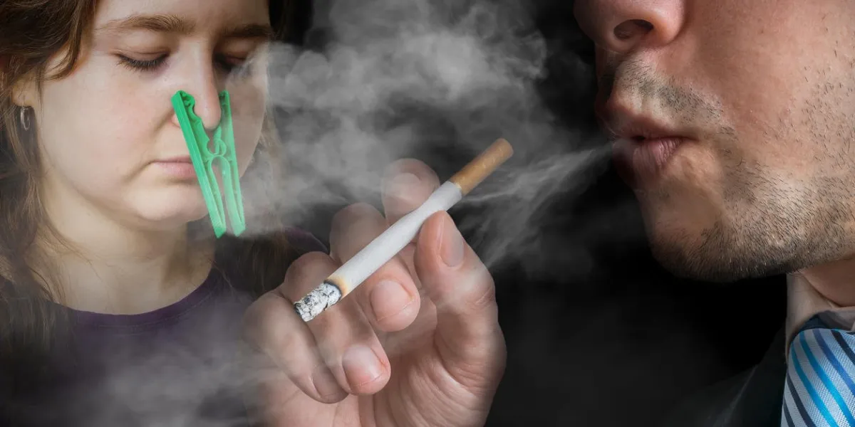 passive smoking concept selfish man is smoking a cigarette woman cant breathe and has peg on her nose