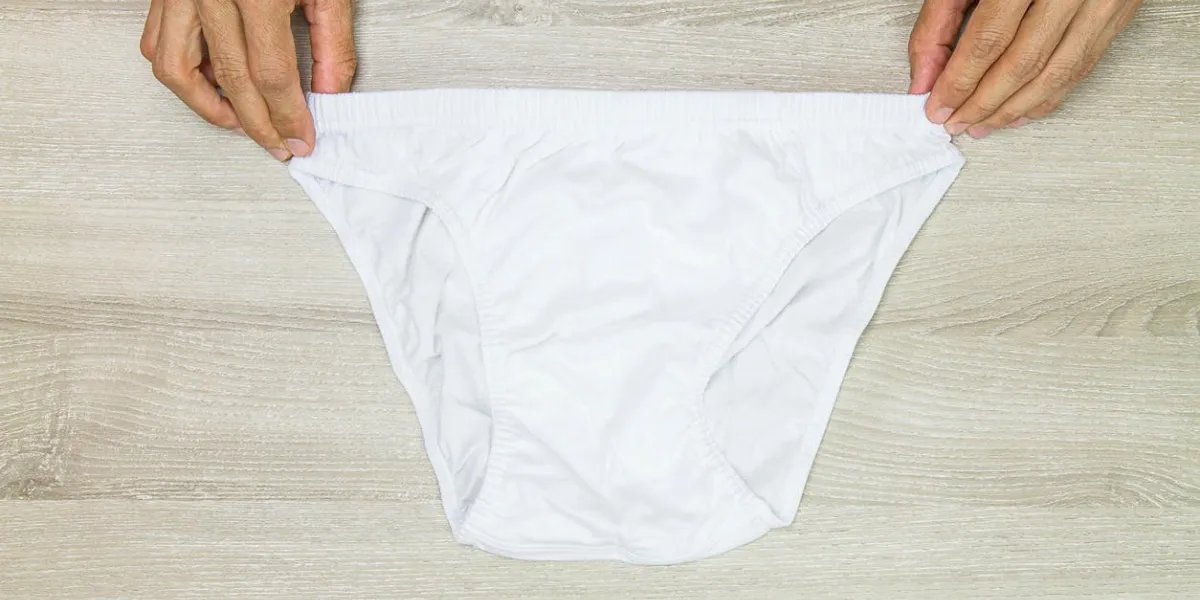 hands holding men white underwear on wooden background