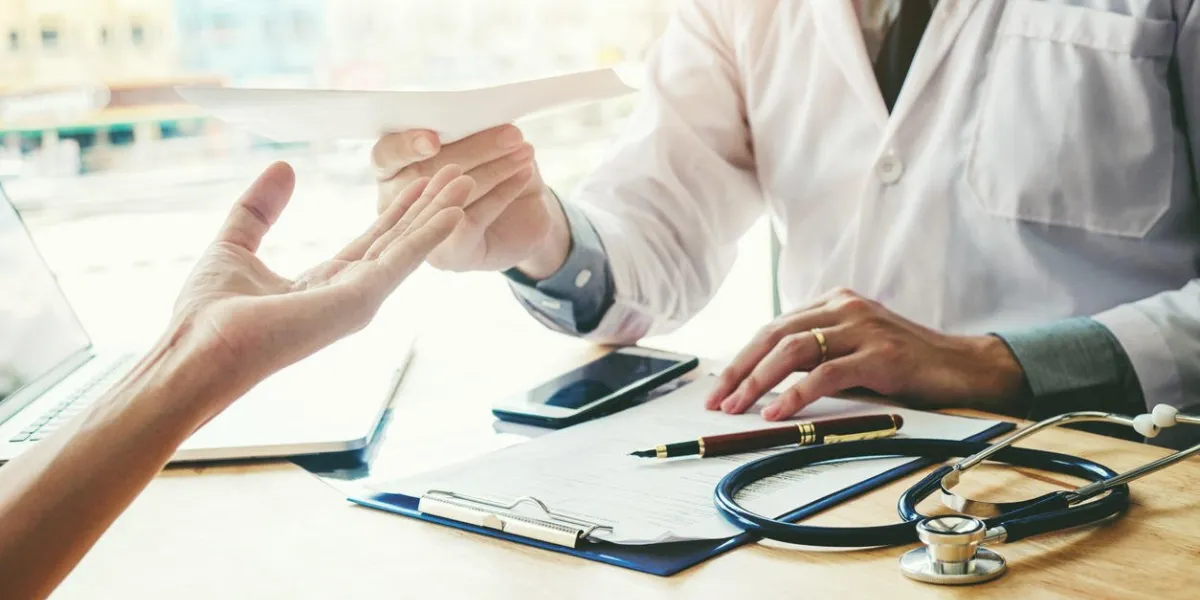 doctor or physician writing diagnosis and giving a medical prescription to female patient