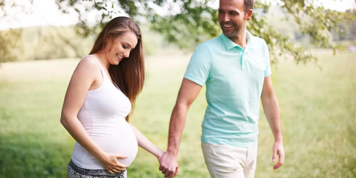 femme enceinte avec mari marchant sur la prairie